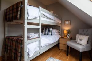a bedroom with a bunk bed and a chair at Tanar View in Aboyne
