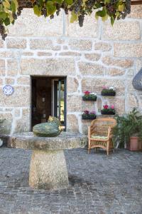 a stone building with a bench and a chair at Quinta da Casa Nova in Santo Tirso