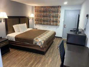 a hotel room with a bed and a flat screen tv at Hillside Motel Glen Mills in Glen Mills