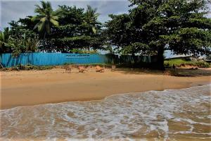 a beach with chairs and a blue fence at OCEAN-SI MAnsion in Kribi