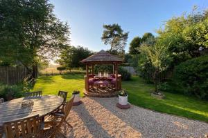 a gazebo in a garden with a table and chairs at ROSE COTTAGE in Rowlands Castle