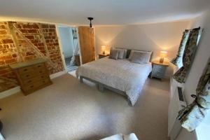 1 dormitorio con cama y pared de ladrillo en ROSE COTTAGE, en Rowlands Castle