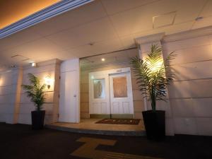a hallway with two plants in front of a door at Hotel Fine Garden Nara Horai in Nara