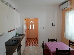 a kitchen with a table and a red door at Apartmani Rija 3 in Pag