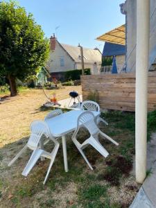 two white chairs and a table in a yard at Maison d'une chambre avec jardin clos et wifi a Saint Patrice in Saint-Patrice