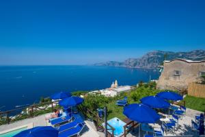 un gruppo di sedie blu e ombrelloni accanto all'acqua di Villa Il Frantoio and Lilmar a Praiano