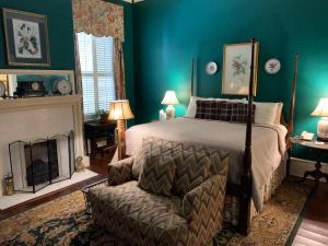 um quarto com uma cama, uma cadeira e uma lareira em 1842 Inn em Macon