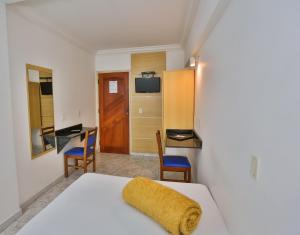 a room with a bed with a yellow towel on it at HOTEL ROTA DO SOL in Praia Grande