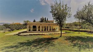 a house in a field with a tree in front of it at Holiday House Vela Vrta in Sveti Ivan Dobrinjski