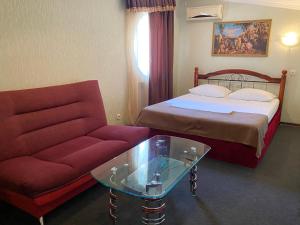 ロストフ・ナ・ドヌにあるHotel KDCのベッド、ソファ、テーブルが備わるホテルルームです。