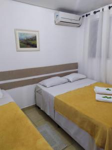 2 camas en una habitación con sábanas amarillas en Hospedaria Ipiranga, en São Paulo