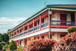 a red and white building with a balcony at Hotel Arrayanes del Quindío in Montenegro