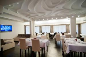 un restaurant avec des tables et des chaises blanches et un plafond dans l'établissement Hotel Dobry Klimat, à Szklarska Poręba