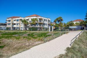 a building on a beach with a walkway at Golden Riviera Absolute Beachfront Resort in Gold Coast