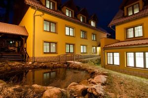 un grand bâtiment jaune avec un étang devant lui dans l'établissement Hotel Dobry Klimat, à Szklarska Poręba