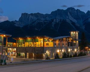 a building with a clock tower in front of mountains at Canmore Downtown Hostel in Canmore