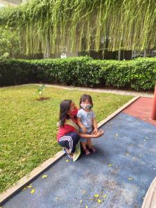 a woman and a little girl sitting on the grass at Altiz Apartment Bintaro Plaza Residence in Tangerang