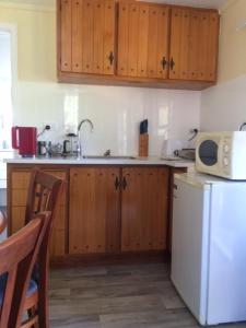 cocina con armarios de madera y nevera blanca en Tui Glen, en Raurimu