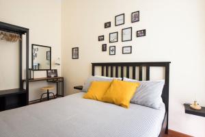 パレルモにあるI Mori di Sicilia by Wonderful Italyのベッドルーム1室(壁に絵画が飾られた黄色い枕のベッド1台付)
