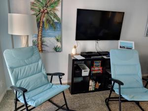 2 sillas en una habitación con TV y escritorio en Space Coast Retreat, en Satellite Beach