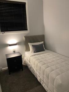 a bedroom with a bed and a nightstand and a window at Apartment 65 Akaroa in Akaroa