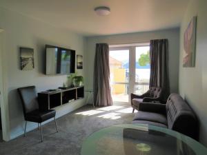 sala de estar con sofá, sillas y mesa de cristal en Apartment 65 Akaroa en Akaroa