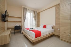 a bedroom with a bed with a window and a desk at RedDoorz Syariah Plus @ Wisma Bougenville Karawaci in Tangerang