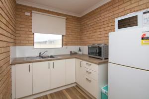 a kitchen with white cabinets and white appliances at Cervantes Pinnacles Motel in Cervantes