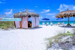 eine kleine Hütte am Strand mit Stühlen und Sonnenschirmen in der Unterkunft Anna Maria Island Beach Palms 7A in Bradenton Beach