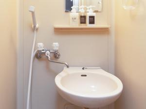 a bathroom with a toilet with a white sink at Tabist Business Ryokan Duck Ishinomaki Hebita in Ishinomaki