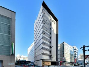a tall white building on a city street at REF Omiya by VESSEL HOTELS in Saitama