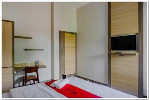 um quarto com uma cama, uma televisão e uma secretária em RedDoorz near Jogja City Mall 4 em Yogyakarta