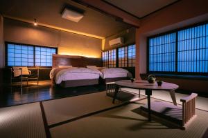 a bedroom with two beds and a table in it at Yasuraginoyado Yufu in Beppu