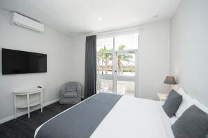 a white bedroom with a bed and a television at The Parade Hotel in Bunbury
