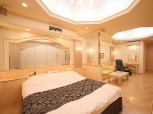 a hotel room with a large bed and a chair at Hotel Fine Garden Senboku in Sakai
