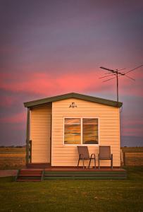 a tiny house with two chairs in front of it at Lang Lang Caravan Park 