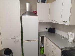 a kitchen with white cabinets and a refrigerator at Olympus Apartment in London