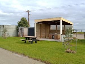 a picnic shelter with a picnic table in the grass at Lang Lang Caravan Park 