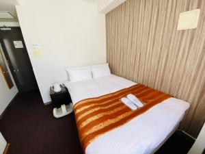 Web Hotel Tokyo Asakusabashi في طوكيو: غرفة فندقية عليها سرير وعليها نعال اثنين