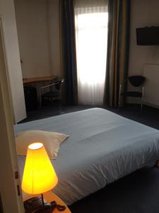 a bedroom with a bed with a yellow lamp and a window at Amadeus Hotel in Sarreguemines