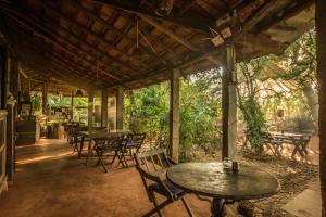 an outdoor patio with tables and chairs and trees at Bhakti Kutir in Palolem