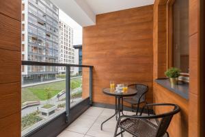 einen Balkon mit einem Tisch und Stühlen sowie einem Fenster in der Unterkunft Rent like home - Grzybowska 85 II in Warschau