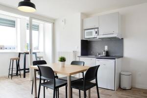 eine Küche und ein Esszimmer mit einem Tisch und Stühlen in der Unterkunft Résidence La Canopée in Straßburg
