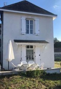 a white house with a table and chairs in front of it at Gîte des Roses in Oradour-Fanais