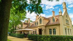 une grande maison avec un parasol devant elle dans l'établissement Cavalierhaus Branitz, à Cottbus