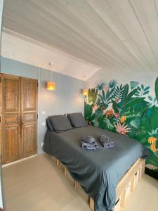 a bedroom with a bed with a tropical mural on the wall at L'annexe de Gaston in Le Port-des-Barques