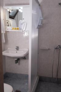 a white bathroom with a sink and a shower at Klio Hotel in Alexandroupoli
