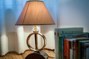 a lamp sitting on a table next to books at Residence Engel in Nova Levante