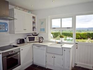 kuchnia z białymi szafkami, umywalką i oknem w obiekcie Fleur Cottage Killorglin by Trident Holiday Homes w mieście Killorglin