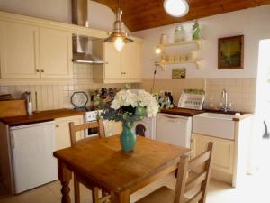 a kitchen with a table with a vase of flowers on it at Kizzie Cottage Killorglin by Trident Holiday Homes in Killorglin